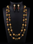 Gold-plated double-strand beaded necklace set with ruby and emerald colour stones displayed on a black mannequin bust with matching drop earrings