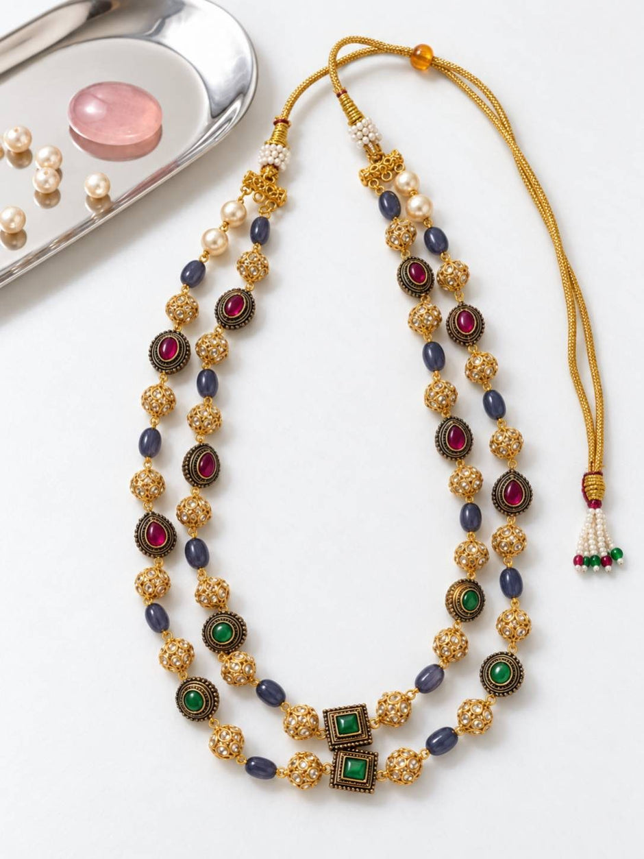 Gold-plated double-strand necklace laid flat showing adjustable dori closure with pearl tassel and filigree ball beads
