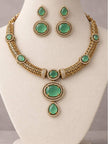 Gold-plated green stone necklace set with drop earrings displayed on a white bust form