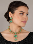 Woman wearing gold-plated green stone necklace and matching circular drop earrings with a black embroidered top