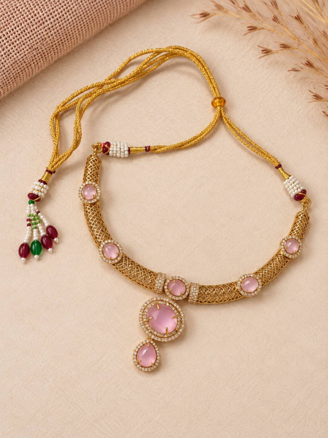 Gold-plated pink stone choker necklace laid flat showing adjustable dori closure with pearl and bead tassels