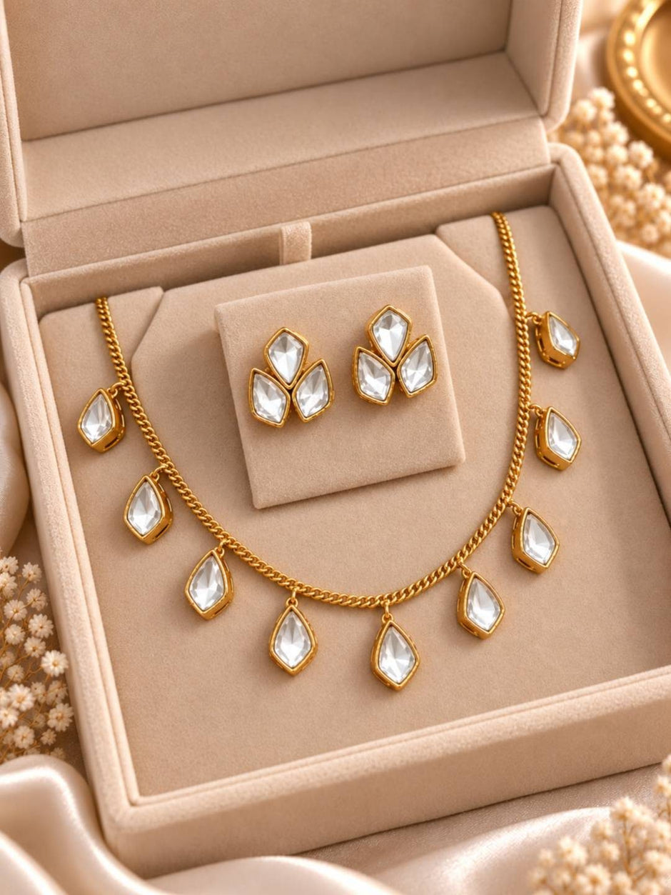 Gold-plated kundan drop necklace and stud earrings displayed inside an open beige velvet jewellery box