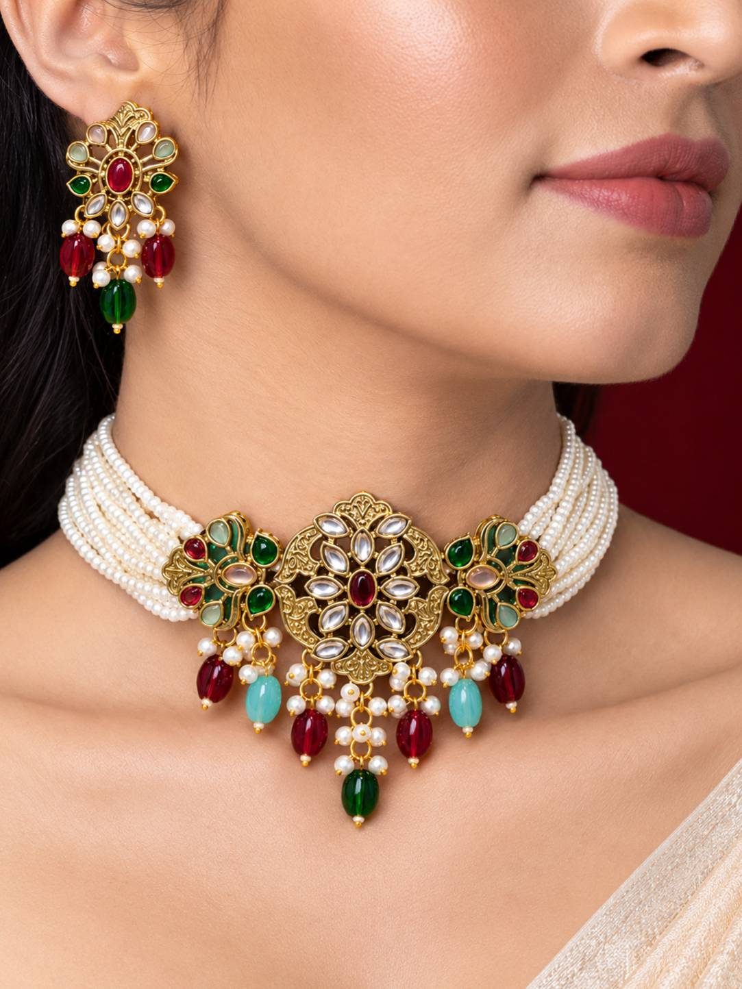 Woman wearing a multi-strand seed pearl choker with gold-tone kundan pendant and coloured bead drops, paired with matching earrings