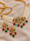 Flat lay of multi-strand seed pearl choker necklace with gold cord ties and two matching kundan drop earrings on beige fabric