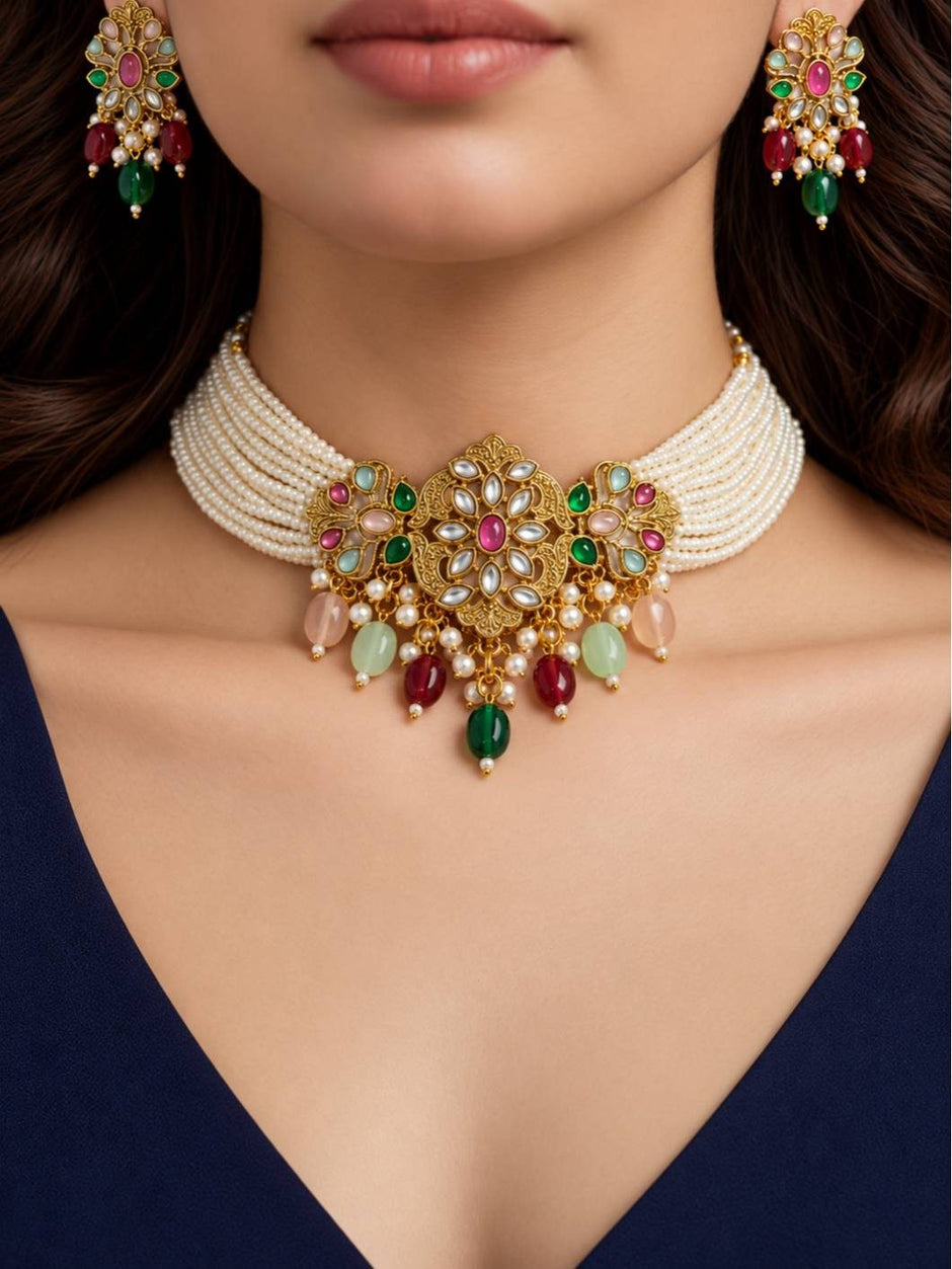 Woman wearing a multi-strand pearl choker with gold kundan pendant and matching earrings against a navy top