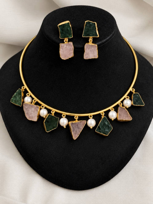Gold-plated choker necklace set with green and pink raw stones and faux pearls displayed on a black jewellery bust with matching drop earrings