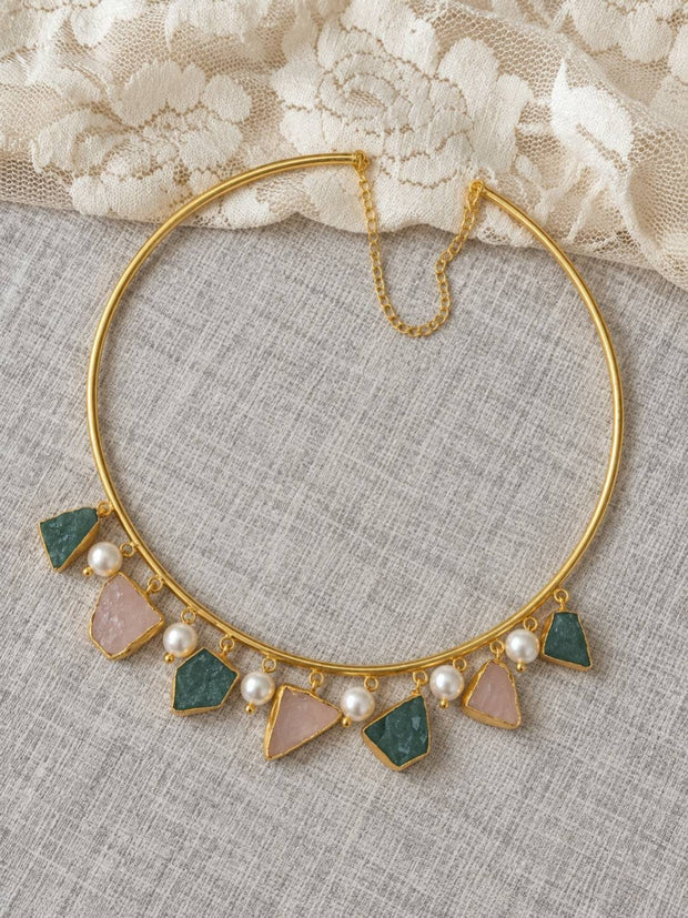 Flat lay of gold-plated raw stone choker necklace with extender chain on a linen fabric background with lace