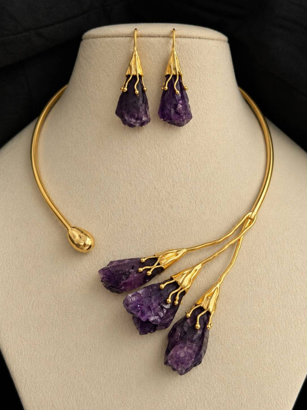 Gold-plated choker with three raw purple amethyst drops and matching hook earrings displayed on a cream jewellery bust