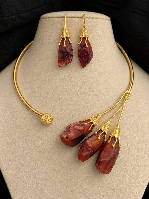 Gold-plated raw stone choker necklace and drop earrings displayed on a cream jewellery bust