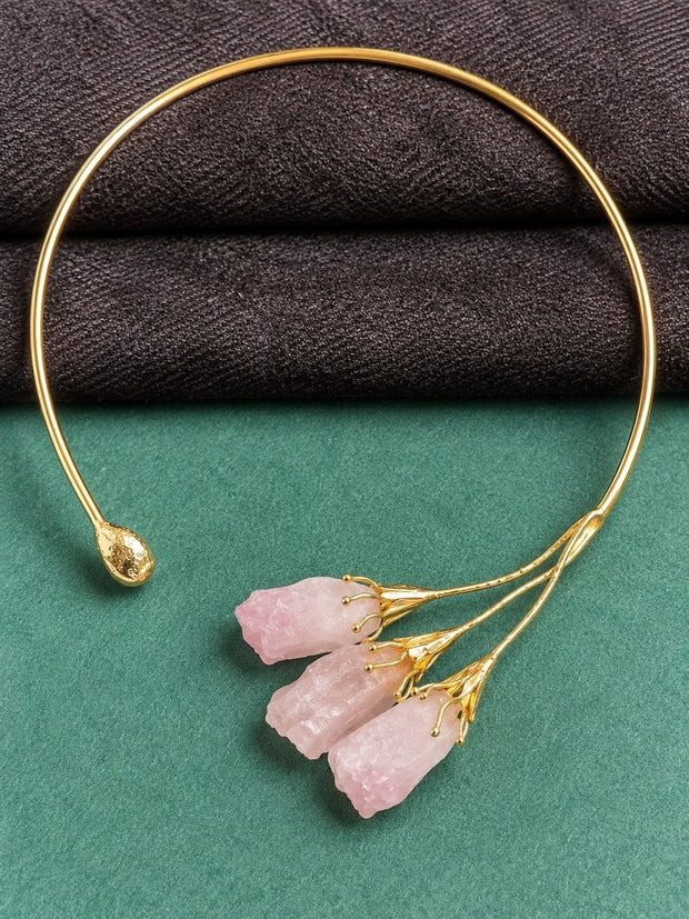 Gold-plated open choker with three raw pink rose quartz drops on green and grey background