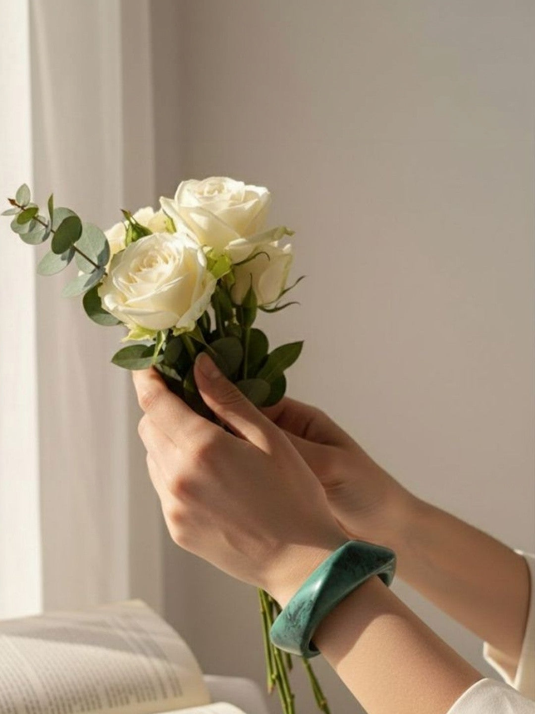 Hands holding white roses wearing a chunky green marble-finish resin bangle on the wrist