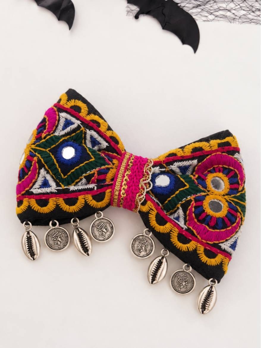 Embroidered multicolour bow hair clip with shisha mirrors and oxidised silver coin and cowrie shell danglers, flat lay view