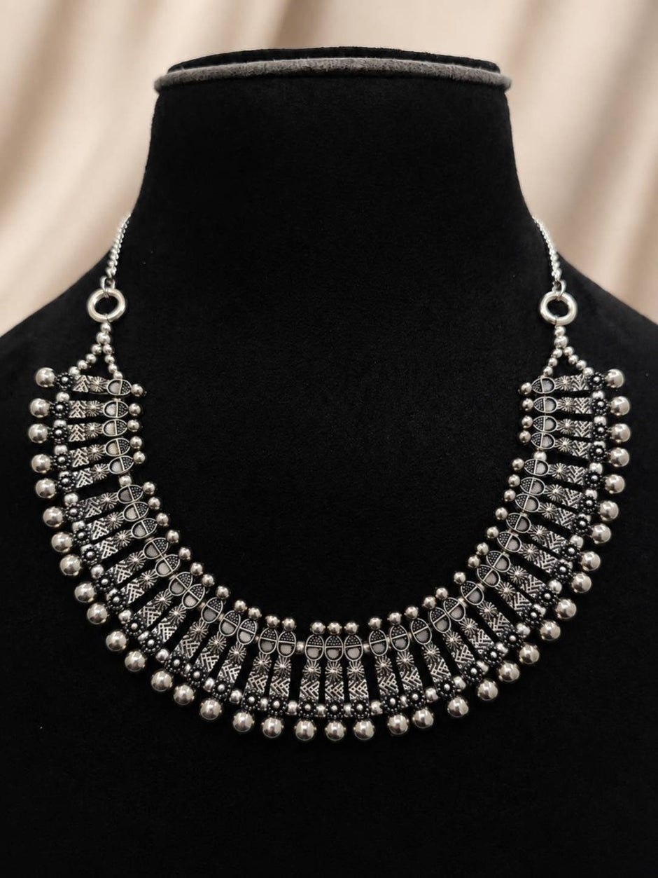 Oxidised silver choker necklace displayed on a black velvet jewellery bust, showing engraved links and dangling ball drops