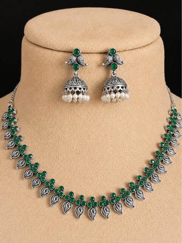 Oxidised silver green stone necklace and jhumka set displayed on a beige jewellery bust
