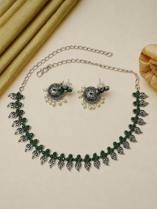 Flat lay of oxidised silver green stone choker necklace with matching stud earrings on cream background