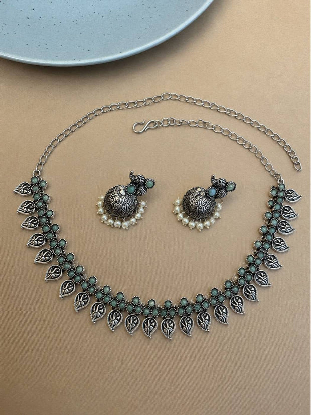 Flat lay of oxidised silver leaf choker and jhumka earrings showing adjustable extension chain