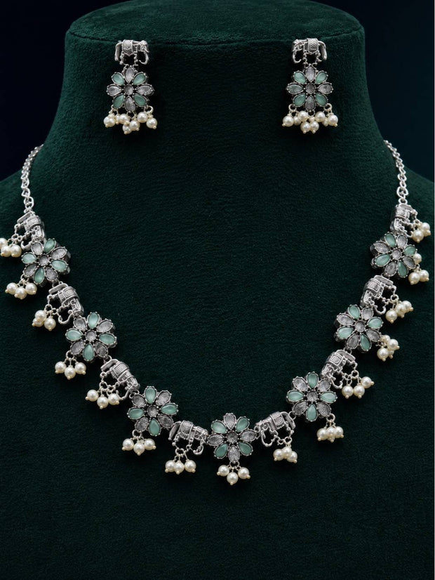 Oxidised silver elephant floral necklace and earring set displayed on a dark green velvet bust