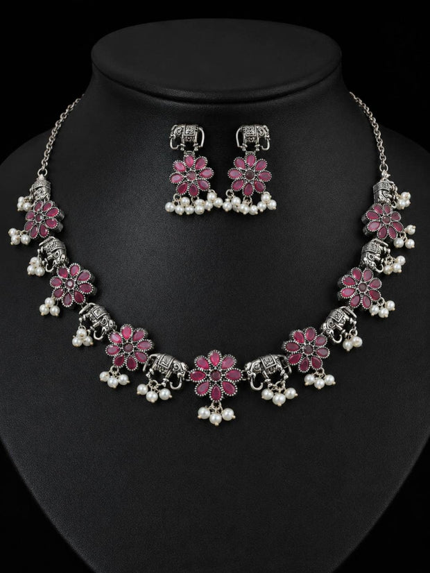 Oxidised silver elephant flower necklace and earring set with pink stones and white pearl drops displayed on a black bust