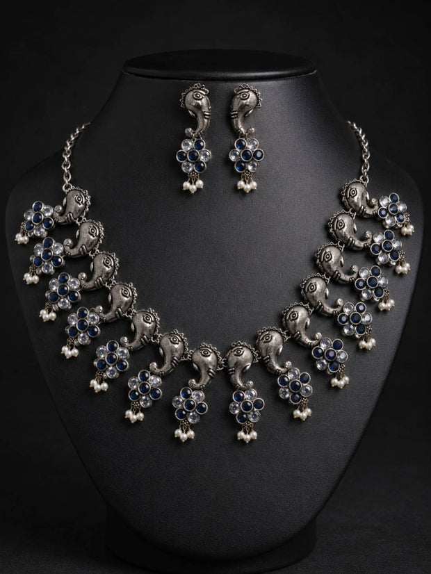 Oxidised silver Ganesha choker necklace set displayed on a black jewellery bust with matching drop earrings