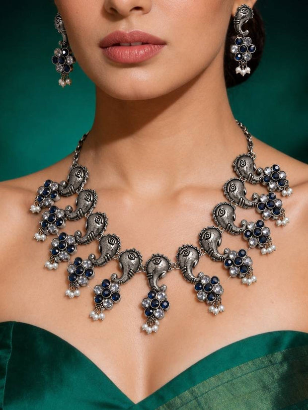 Model wearing oxidised silver Ganesha choker necklace and earrings with a green silk saree