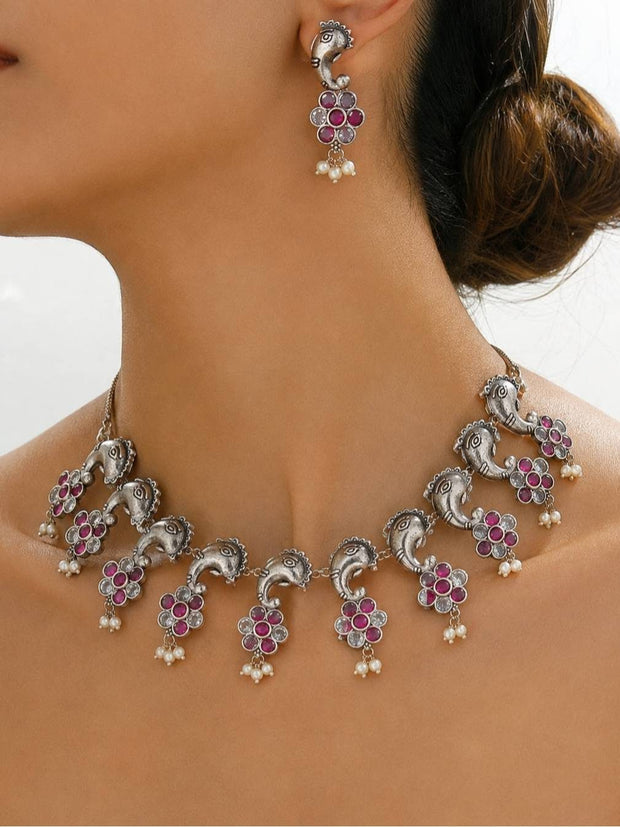 Model wearing oxidised silver peacock necklace with ruby stone flower pendants and matching peacock drop earring