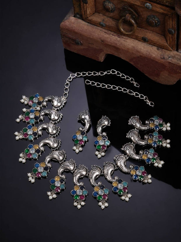 Oxidised silver elephant motif choker necklace with multicolour stone floral clusters laid flat near a wooden box