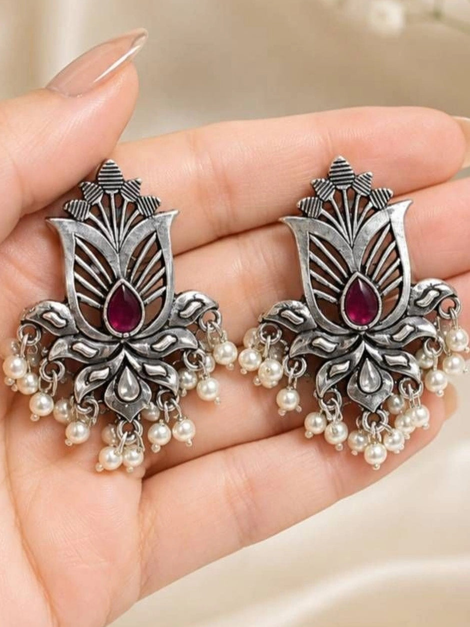 Both oxidised silver lotus stud earrings resting on a woman's open palm showing open-cut floral detail and pearl drops