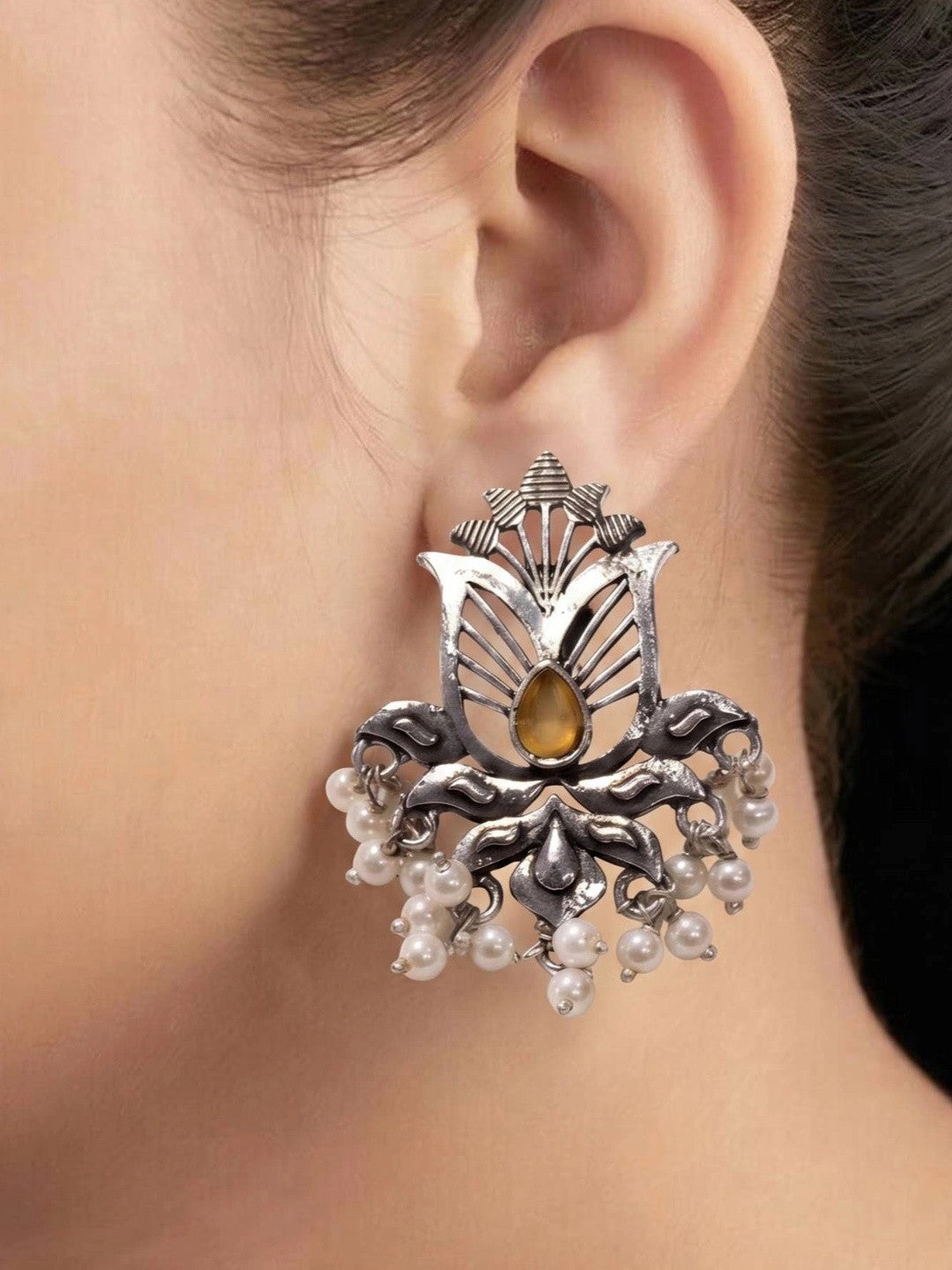 Oxidised silver lotus stud earring with pearl drops worn on a model's ear showing full size