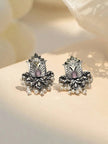 Pair of oxidised silver lotus stud earrings with pink teardrop stone and white pearl drops on cream surface