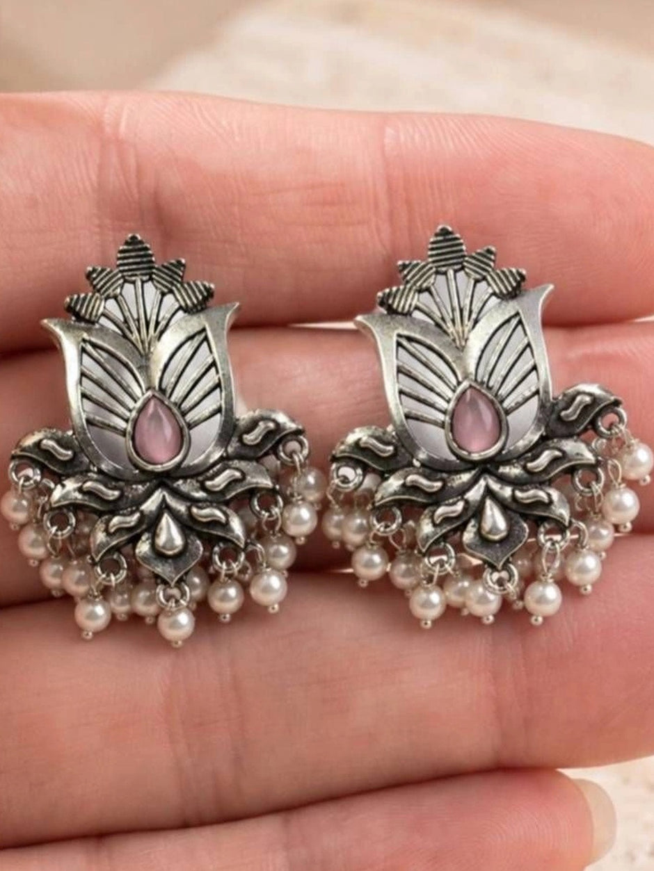 Pair of oxidised silver lotus stud earrings with pink stone and pearl drops held in open palm