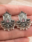 Pair of oxidised silver lotus stud earrings with pink stone and pearl drops held in open palm
