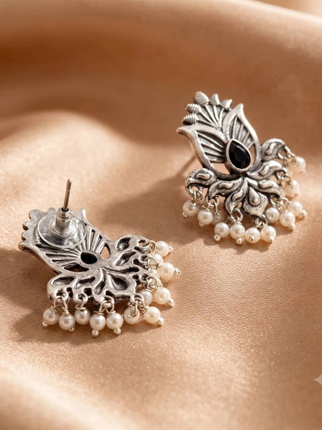Front and back view of oxidised silver lotus earrings showing push-back stud fitting and pearl drops on peach fabric