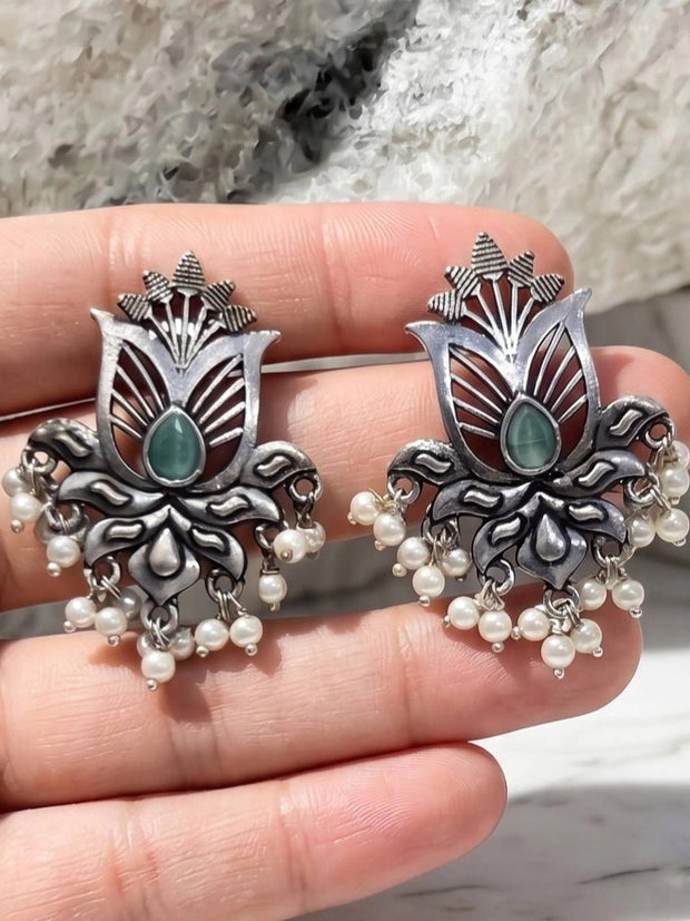 Pair of oxidised silver lotus earrings with pearl drops held in open palm
