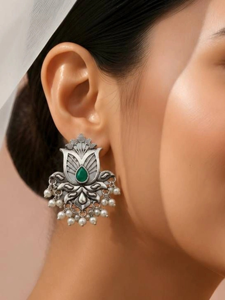 Oxidised silver lotus stud earring worn on a model's ear, showing scale and fit against warm skin tone