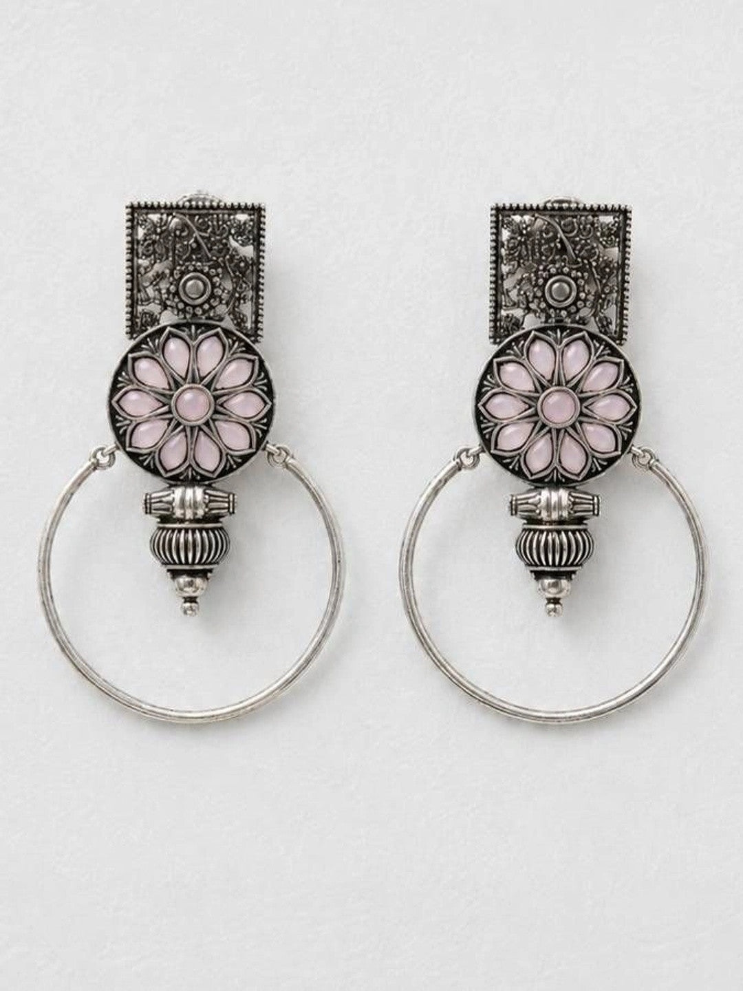 Pair of oxidised silver floral hoop earrings laid flat on a white marble surface
