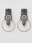 Pair of oxidised silver floral hoop earrings laid flat on a white marble surface