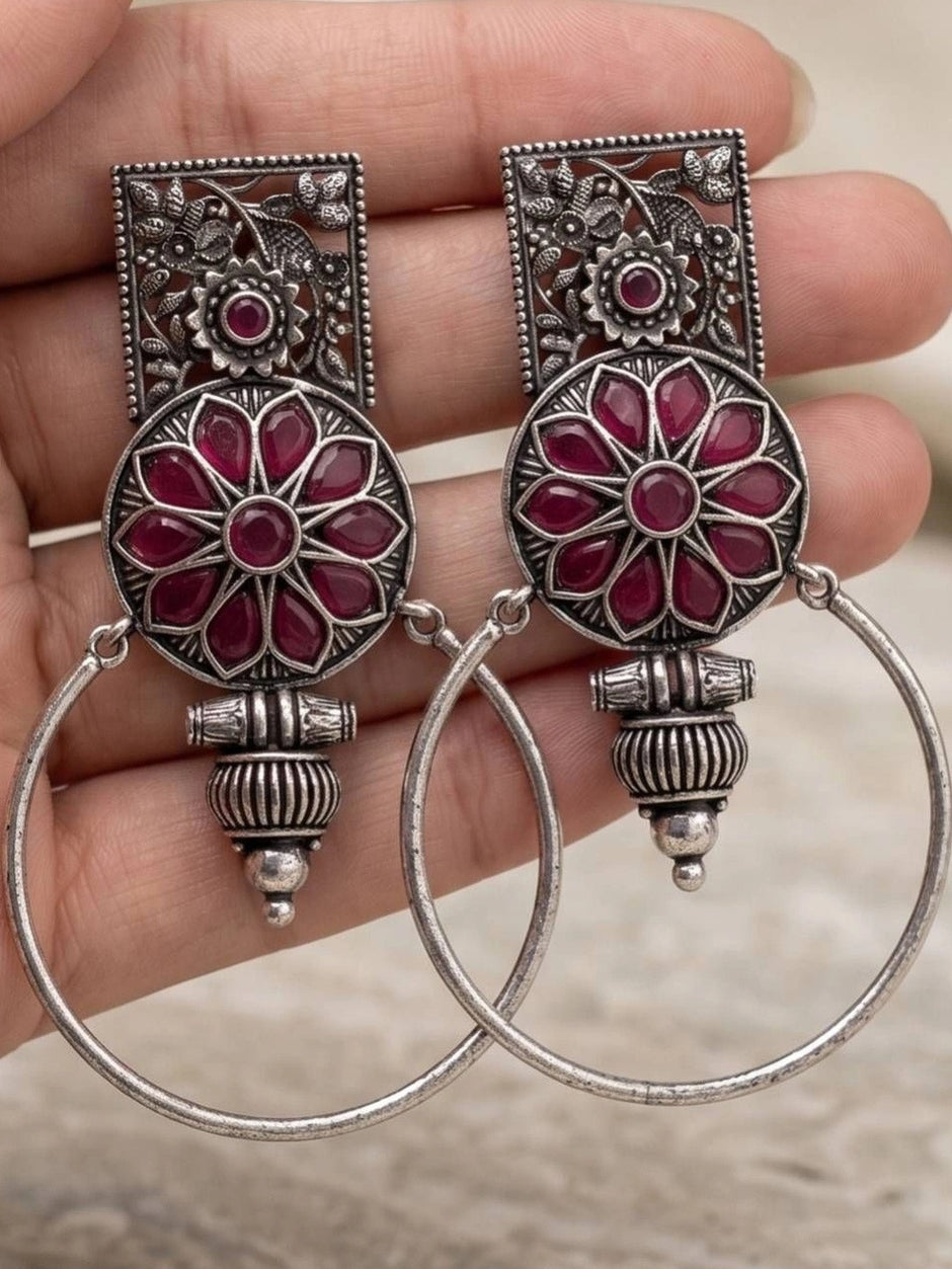 Both oxidised silver floral hoop earrings resting on an open palm showing front detail