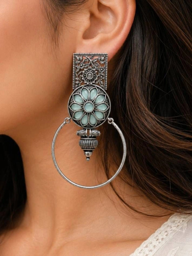 Oxidised silver floral hoop earring worn on a woman's ear showing full drop length