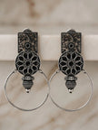 Pair of oxidised silver floral hoop earrings with black resin mandala disc displayed upright against a marble background