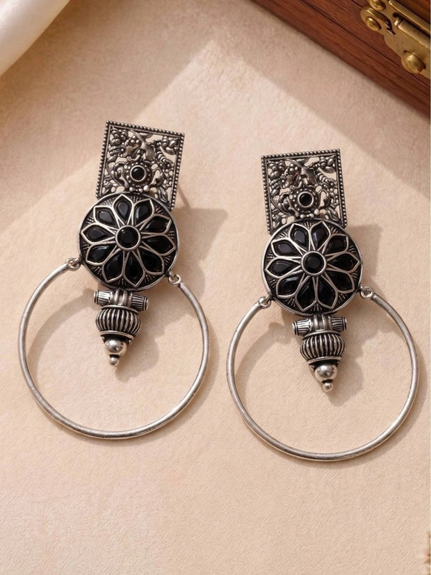 Both oxidised silver hoop earrings laid flat on a cream surface showing engraved rectangular top and mandala disc detail