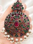 Single oxidised chandbali earring held in a hand, showing detailed ruby and green stone setting and cascading pearl drops