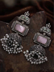 Two oxidised silver jhumka earrings lying on a dark wooden surface showing pearl drop detail