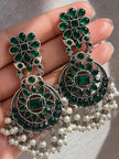 Close-up of oxidised silver chandbali earrings with green glass stones held in palm