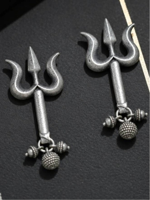Two oxidised silver trishul earrings with beaded charms laid flat on a dark surface