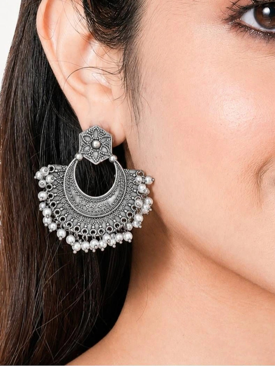Oxidised silver chandbali earring worn on a woman's ear showing size and drape of pearl drops