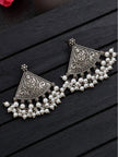 Two oxidised silver chandbali earrings with engraved floral motifs and pearl clusters laid flat on dark wood