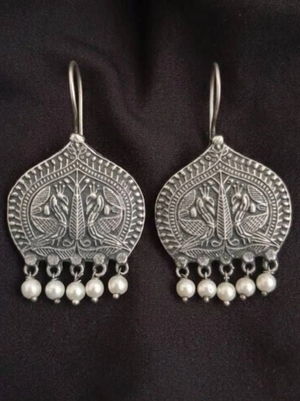 Pair of oxidised silver peacock engraved drop earrings with five white pearl dangles on black background