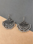 Pair of oxidised silver chandbali earrings with peacock crest and white pearl bead fringe on neutral background