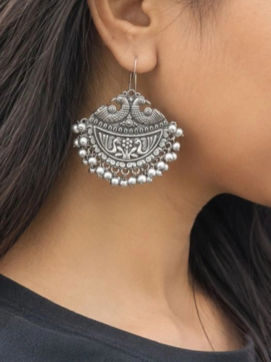Oxidised silver peacock chandbali earring worn on woman's ear showing scale and drape against dark hair