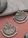 Two oxidised silver chandbali earrings with pearl drops displayed on stone and pink surface showing front detail
